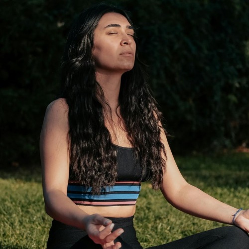 a woman sitting on a blanket in a grassy area