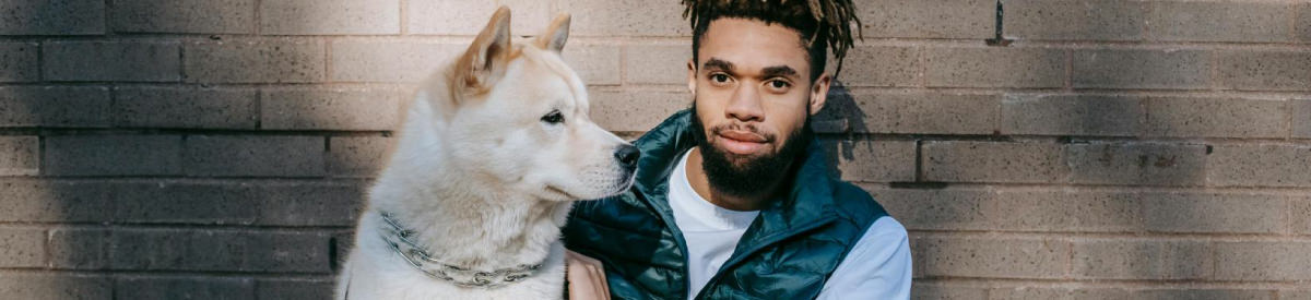 man sitting with dog along a wall